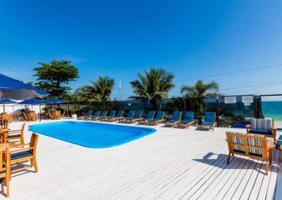 vista da piscina e das cadeiras de sol do Hotel na beira da praia